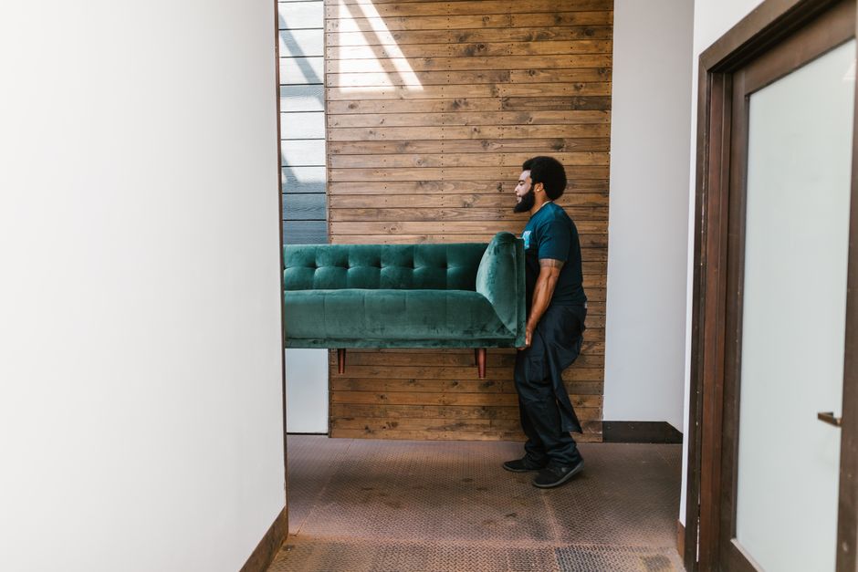 Movers carefully carrying heavy furniture out of a residence